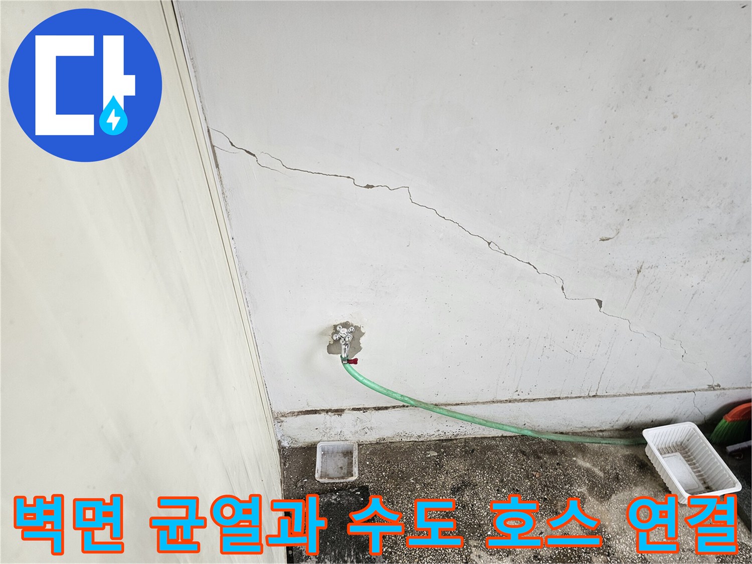 벽면에 발생한 균열 아래 노출된 수도 배관과 호스 모습