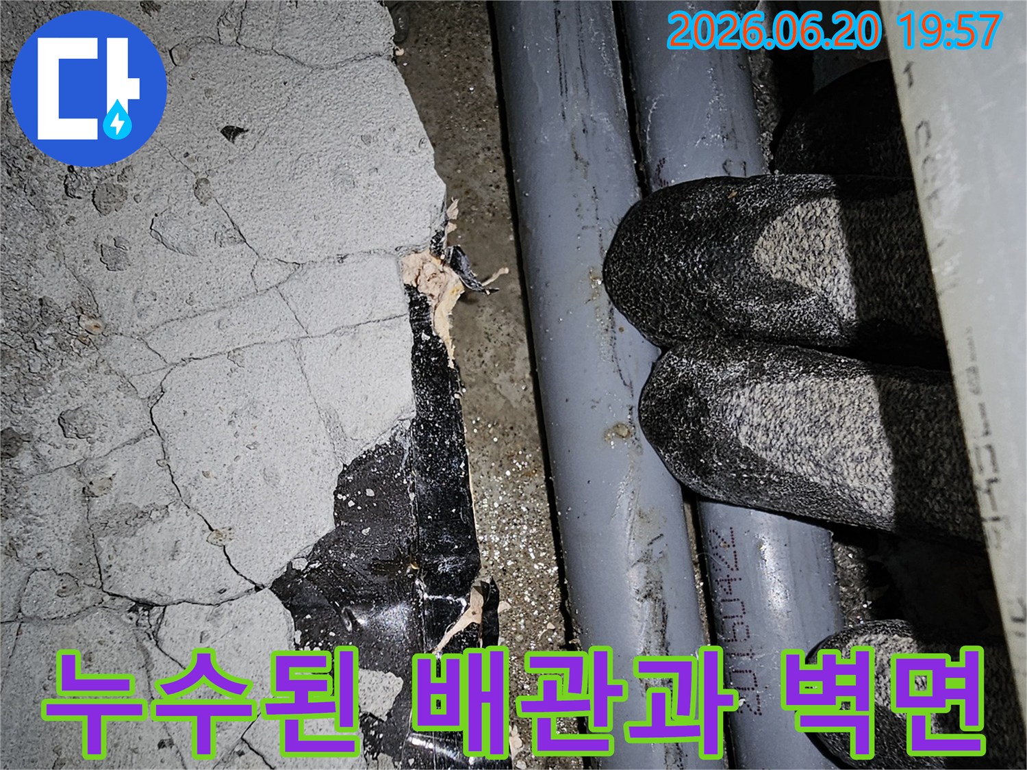 균열이 발생한 콘크리트 벽면과-노출된 배관 주변의-누수 현장을 보여줍니다