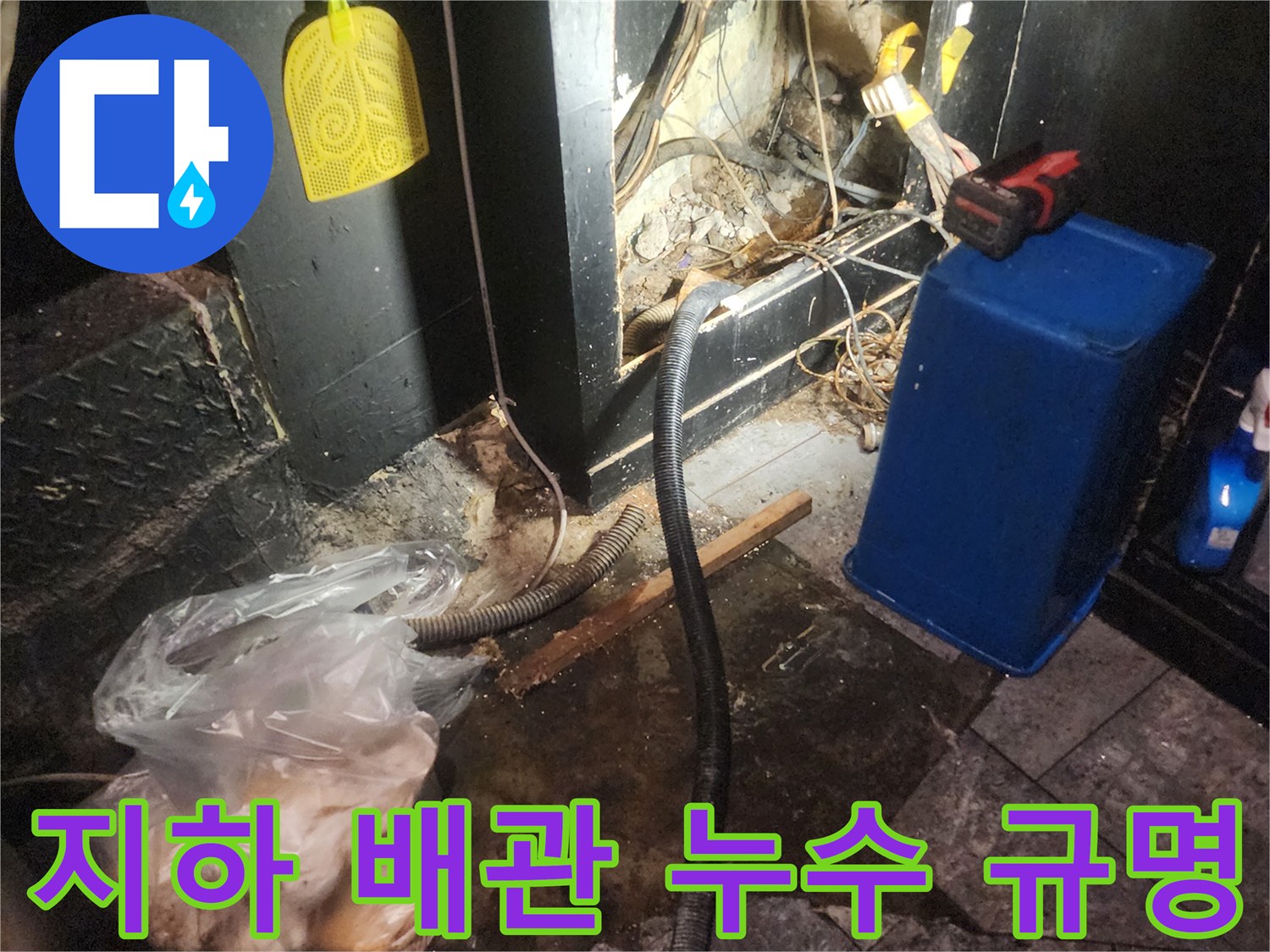 어둡고 습한 지하 공간에서 복잡한 배관과 전선-그리고 물이 고여있는 바닥을 보여주며 누수 원인을 규명하는 현장 사진