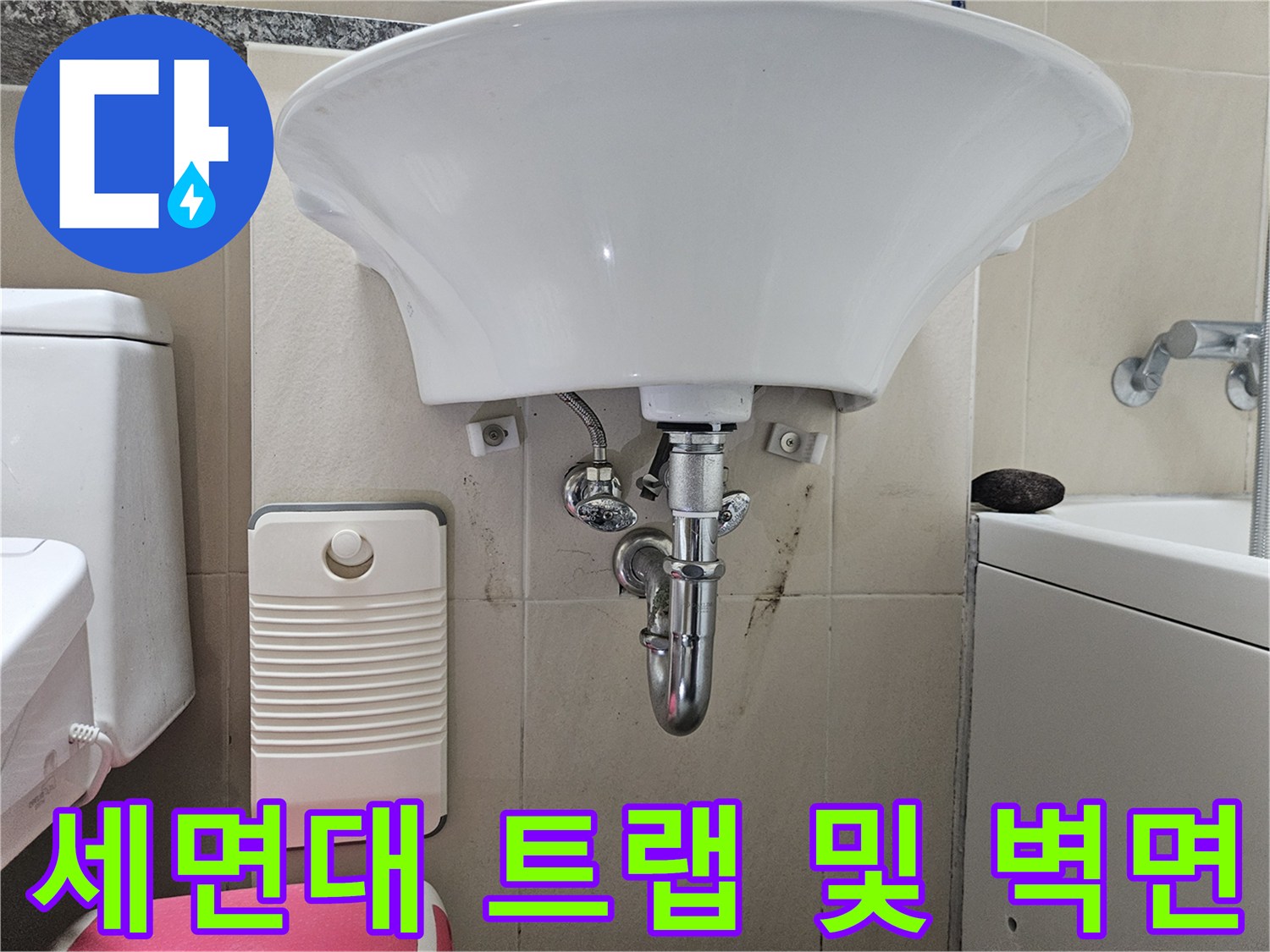 세면대 하부의 배수 트랩과 오염된 타일 벽면을 촬영한 사진입니다.