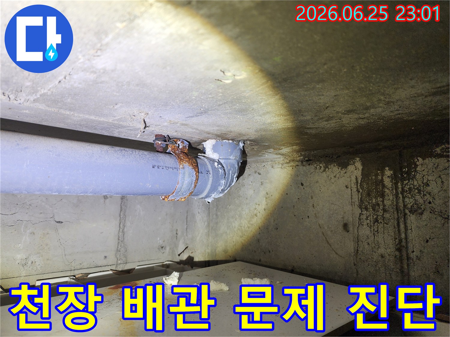 플래시 불빛 아래-심하게 녹슨 배관-클램프와 이음새-그리고 물이 흐른 자국