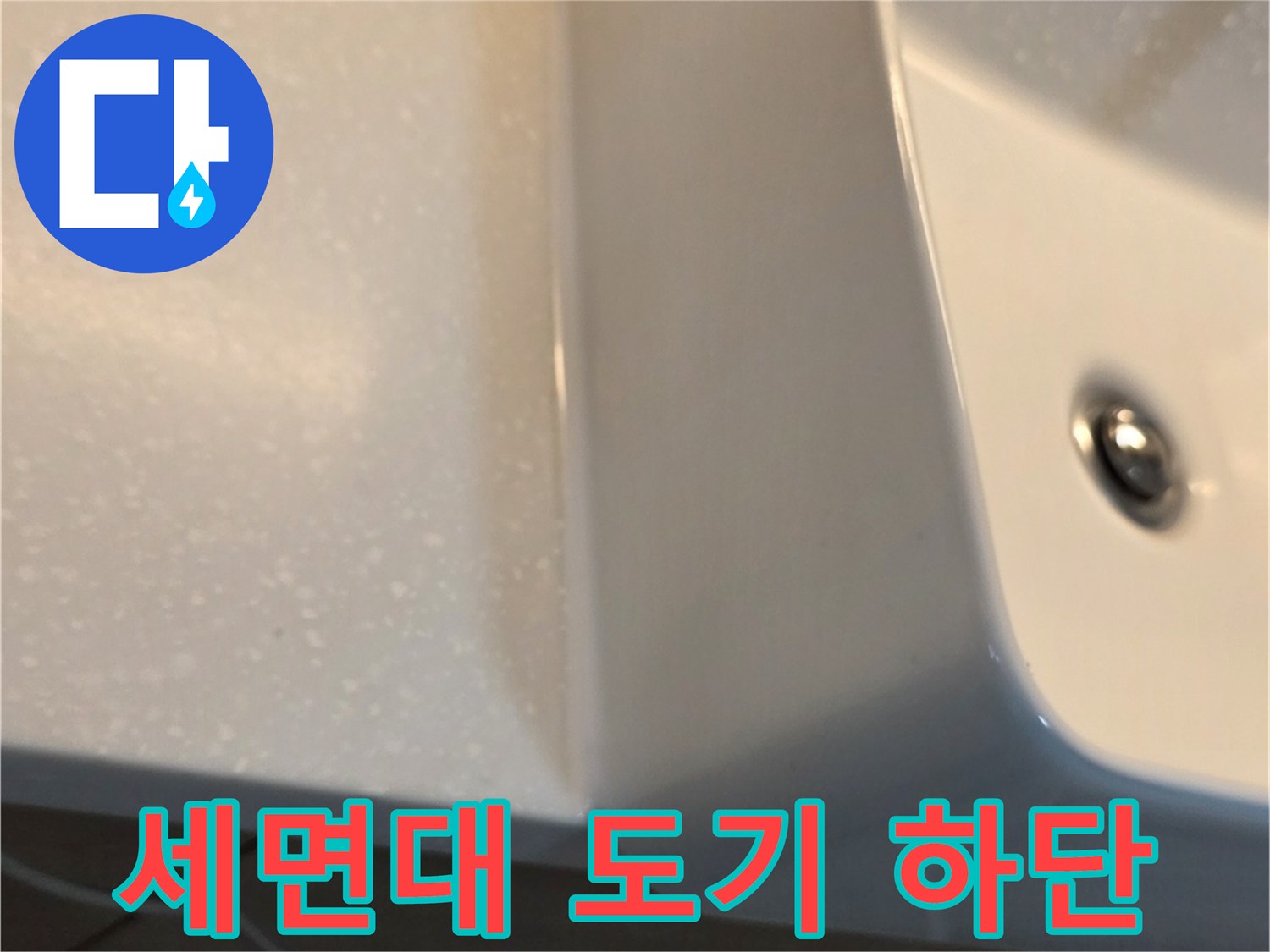 세면대 아래쪽 타일과 도기 사이의 접합부 근접 촬영