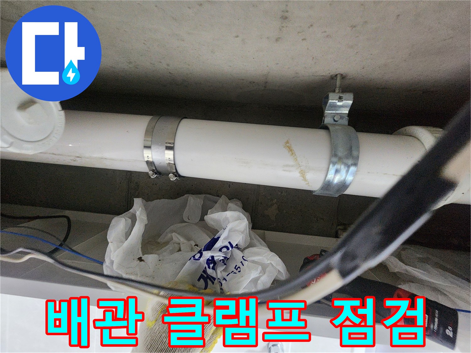 천장 배관을 잡아주는 금속 클램프와 흰색 배관의 상세 모습입니다.