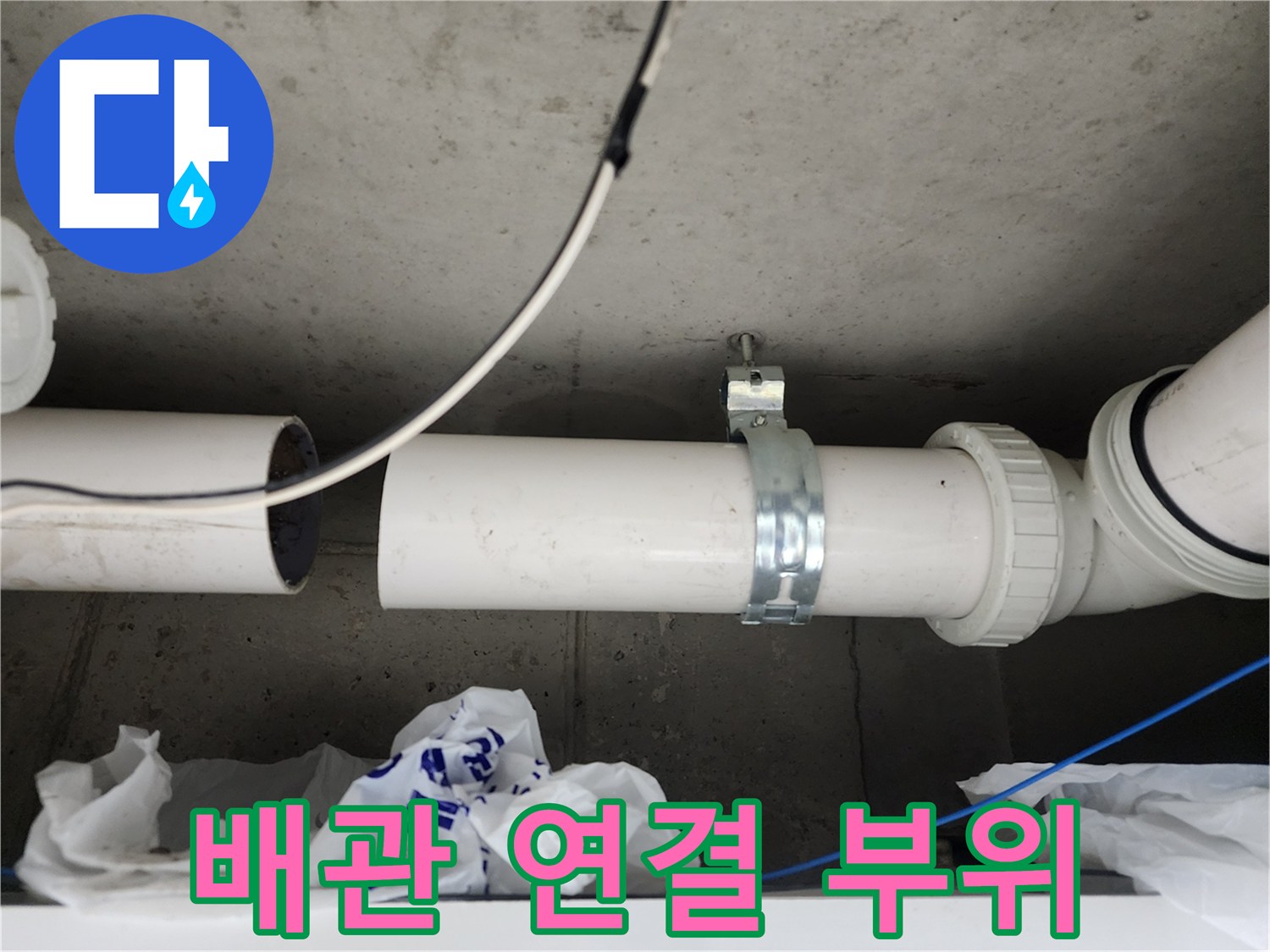 흰색 PVC 배관의 연결부와 금속 고정 장치 상세