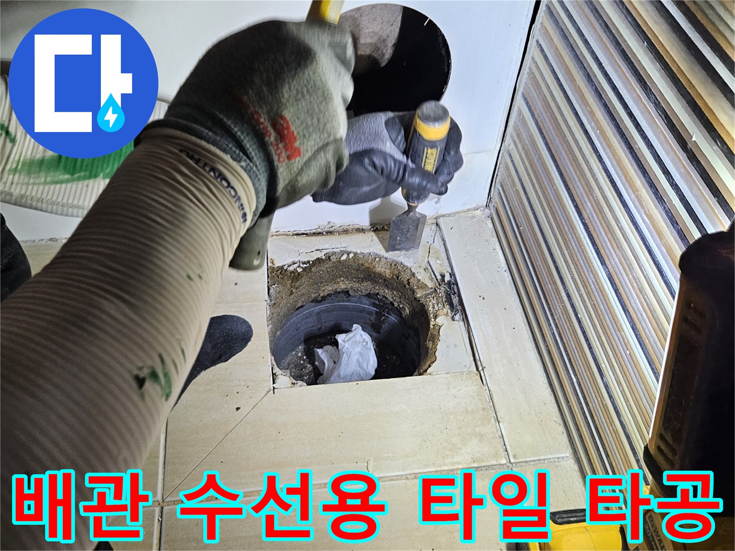 드릴을 사용하여 욕조 옆면의 타일을 파쇄하고 배관을 노출하는 중입니다.