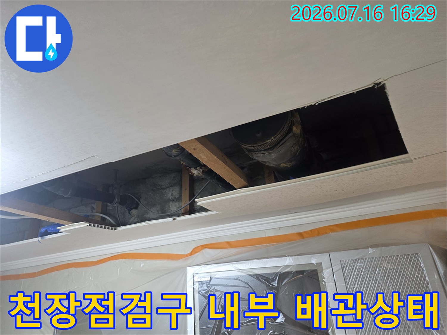 천장 점검구 안쪽의 노출된 배수 및 오수 배관 계통을 조사하는 모습