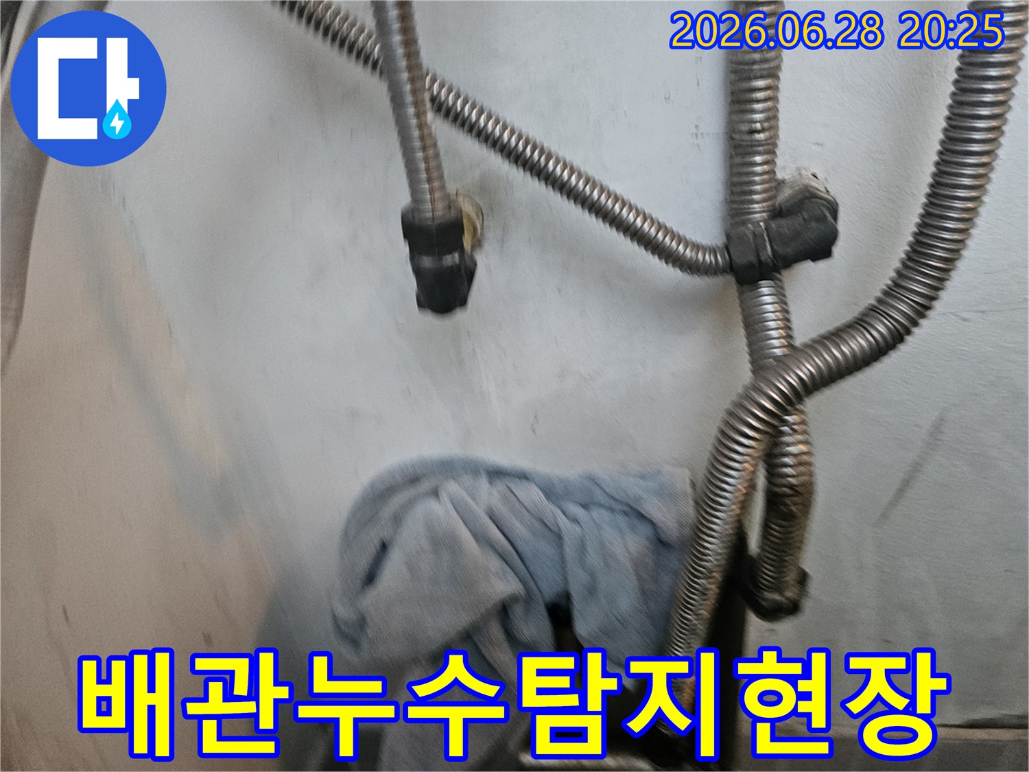 누수 현장에서-유연한 금속 호스와-젖은 수건이-보이는-배관 점검 사진