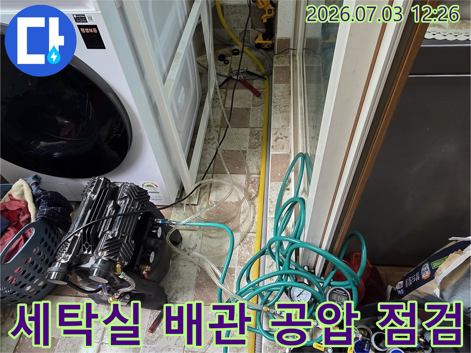 세탁기 옆 공간에서 진행되는 배관 압력 점검 장비와 호스 연결 모습