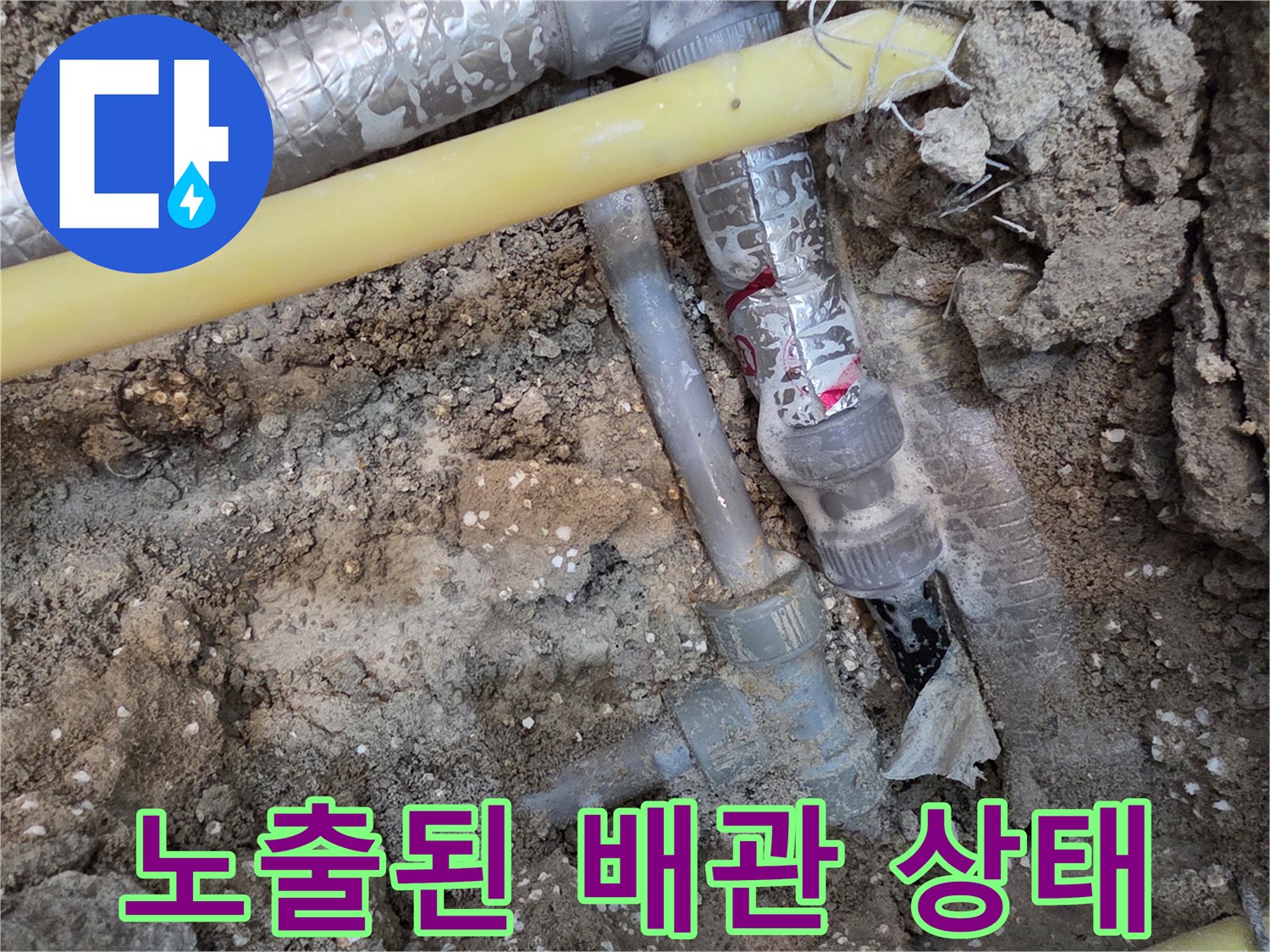 흙 속에 드러난 은박 보온재 배관과 노란색 관