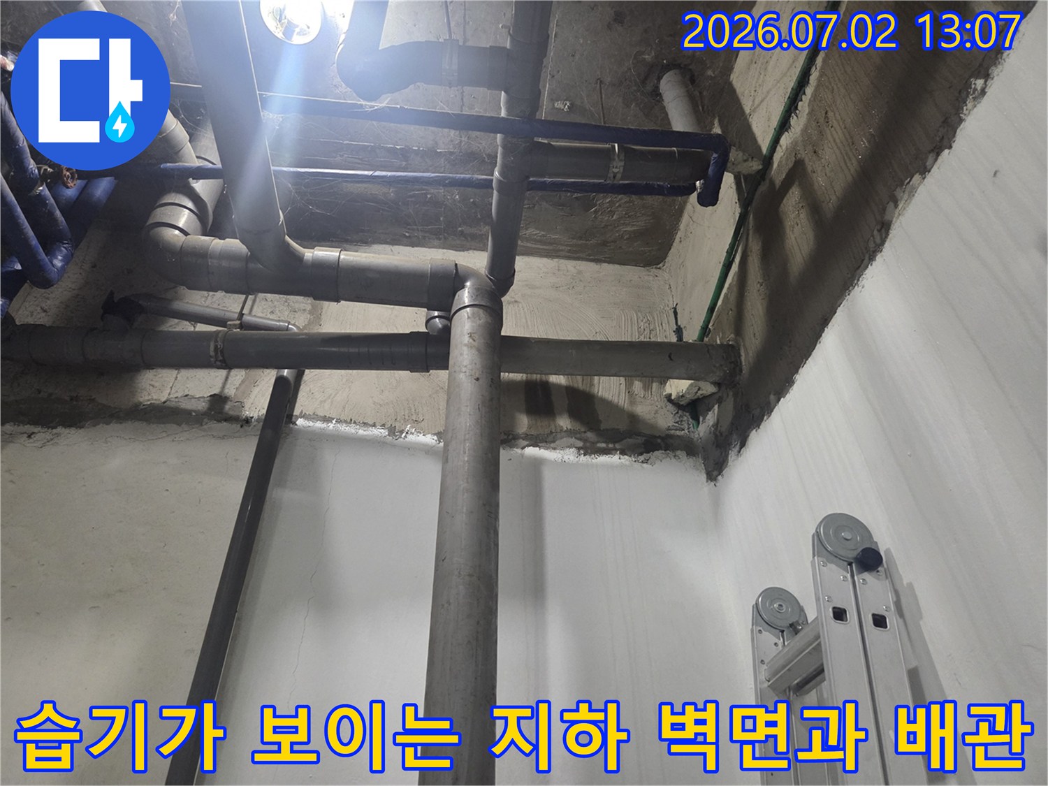 회색 하수 배관이 수직과 수평으로 교차하며 설치된 지하 공간의 전경
