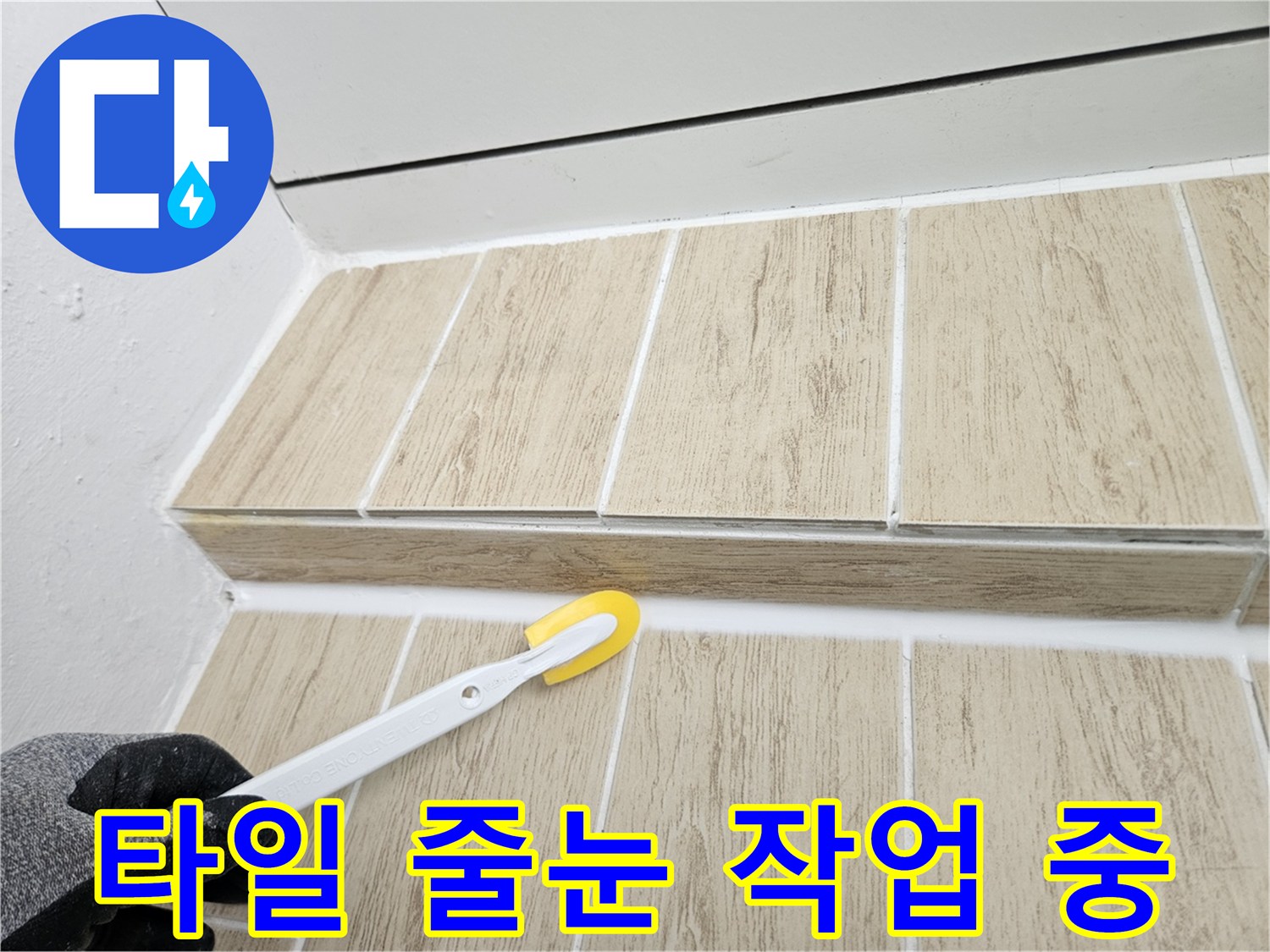 베란다 타일 사이의 흰색 줄눈을 도구로 채워 넣는 모습
