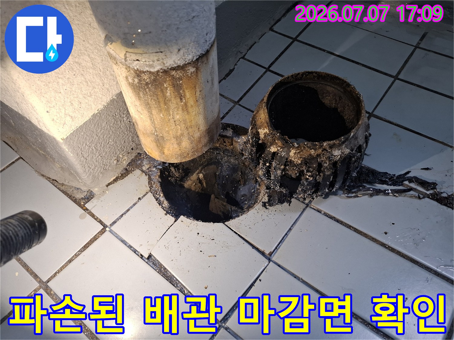 우수관 주변의 노출된 배관과 파손된 방수 층을 촬영한 사진