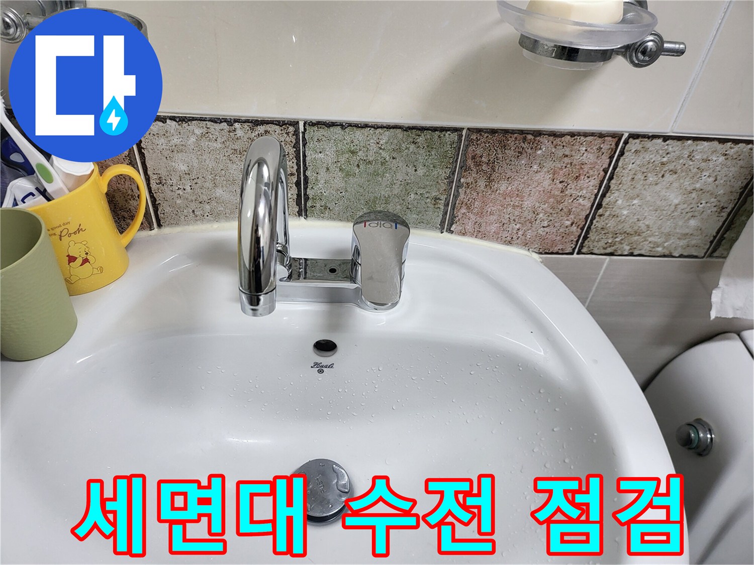 물기가 맺힌 세면대 수전과 타일 벽면입니다.