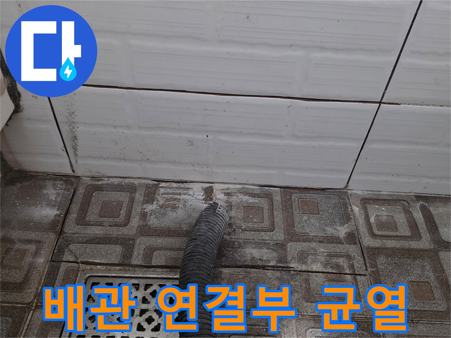 타일 아래 노출된 검은색 배관의 파손된 연결 부위