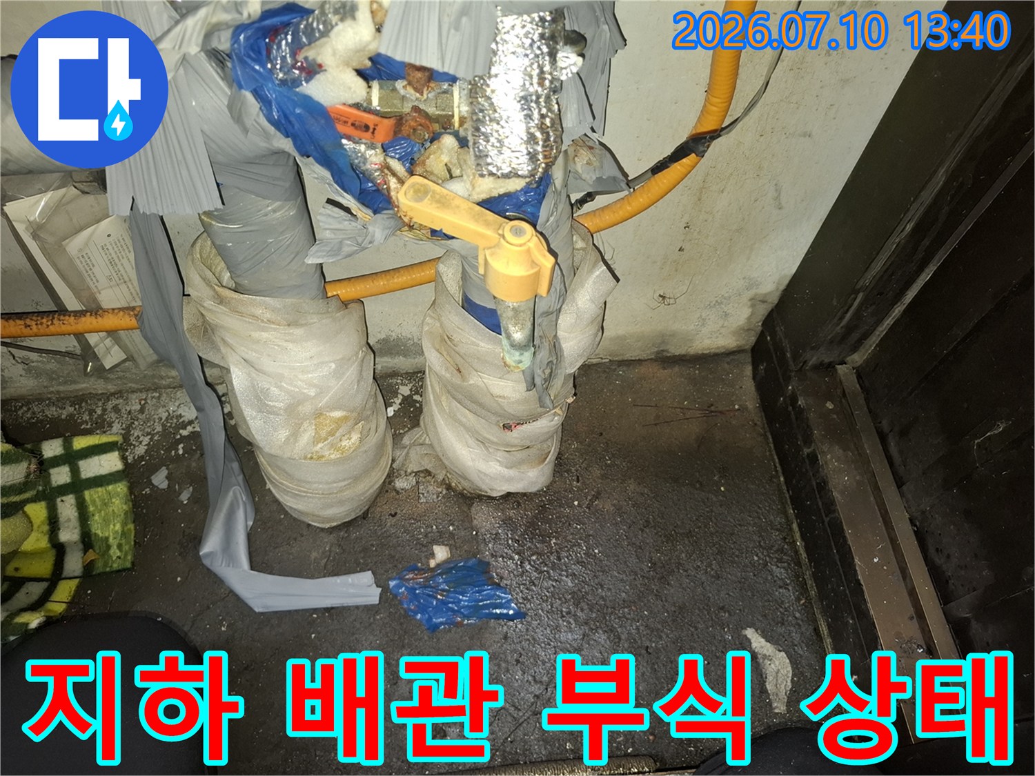 부식된 금속관과 노란색 밸브가 포함된 복잡한 배관 구조의 모습