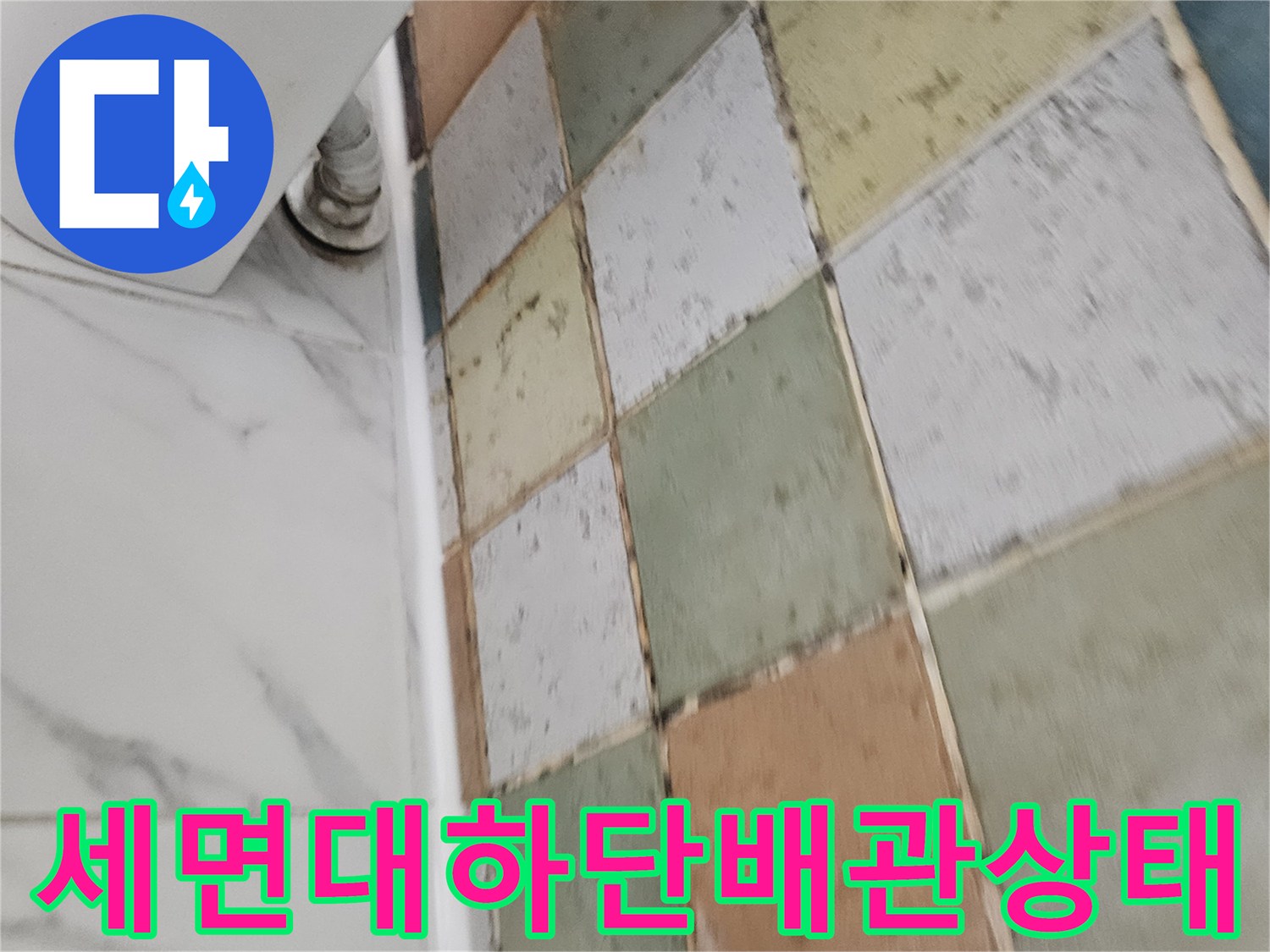 알록달록한 타일 벽면에 설치된 세면대 급수 밸브와 배관