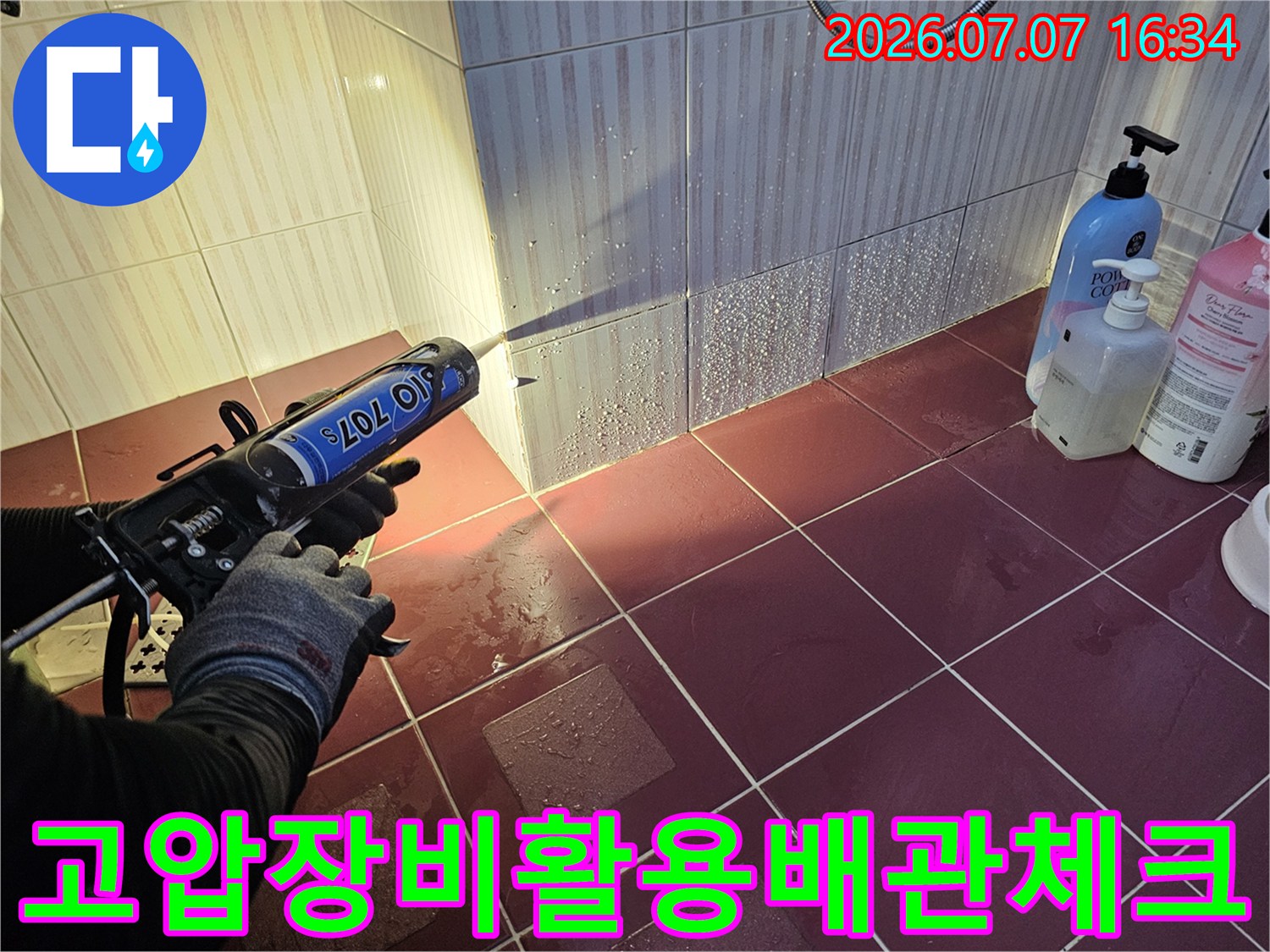 화장실 내 벽면에 위치한 배수 배관 라인을 전문 장비로 세밀하게 점검하는 모습