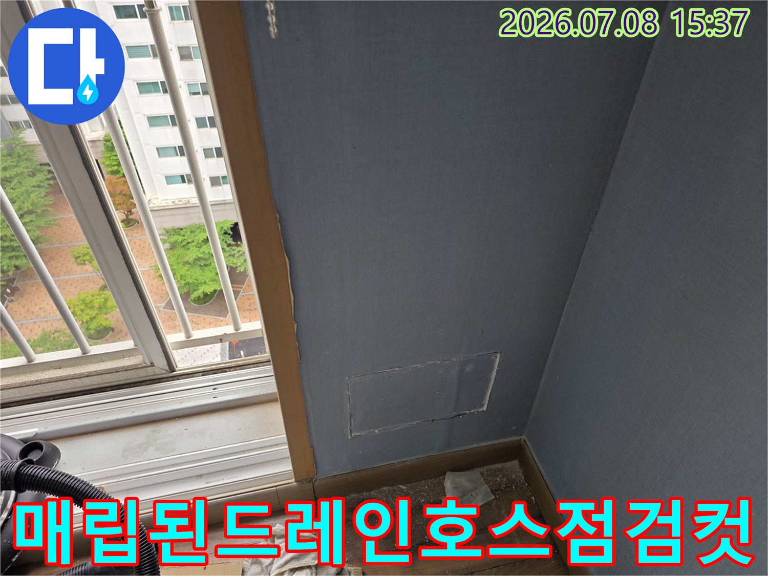 벽면 절개 부위를 통해 드러난 에어컨 배수용 호스의 연결 상태를 점검하는 장면입니다.