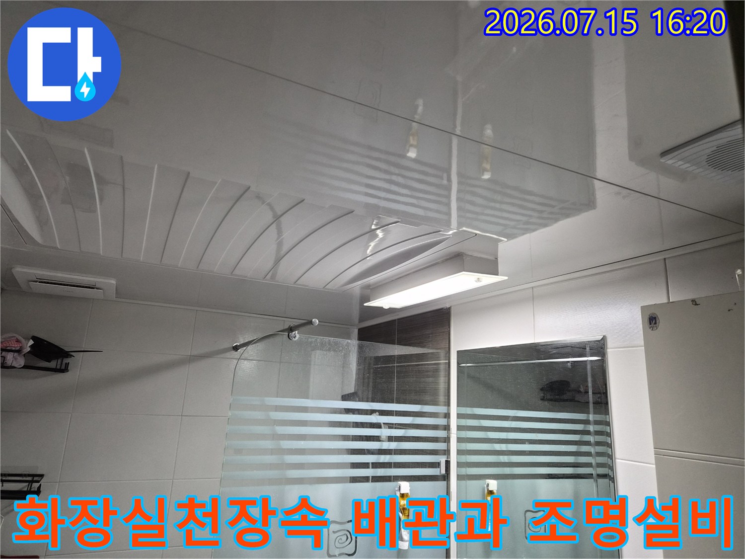 화장실 천장 내부의 노출된 배관과 설치된 환풍기 및 조명 기구 모습