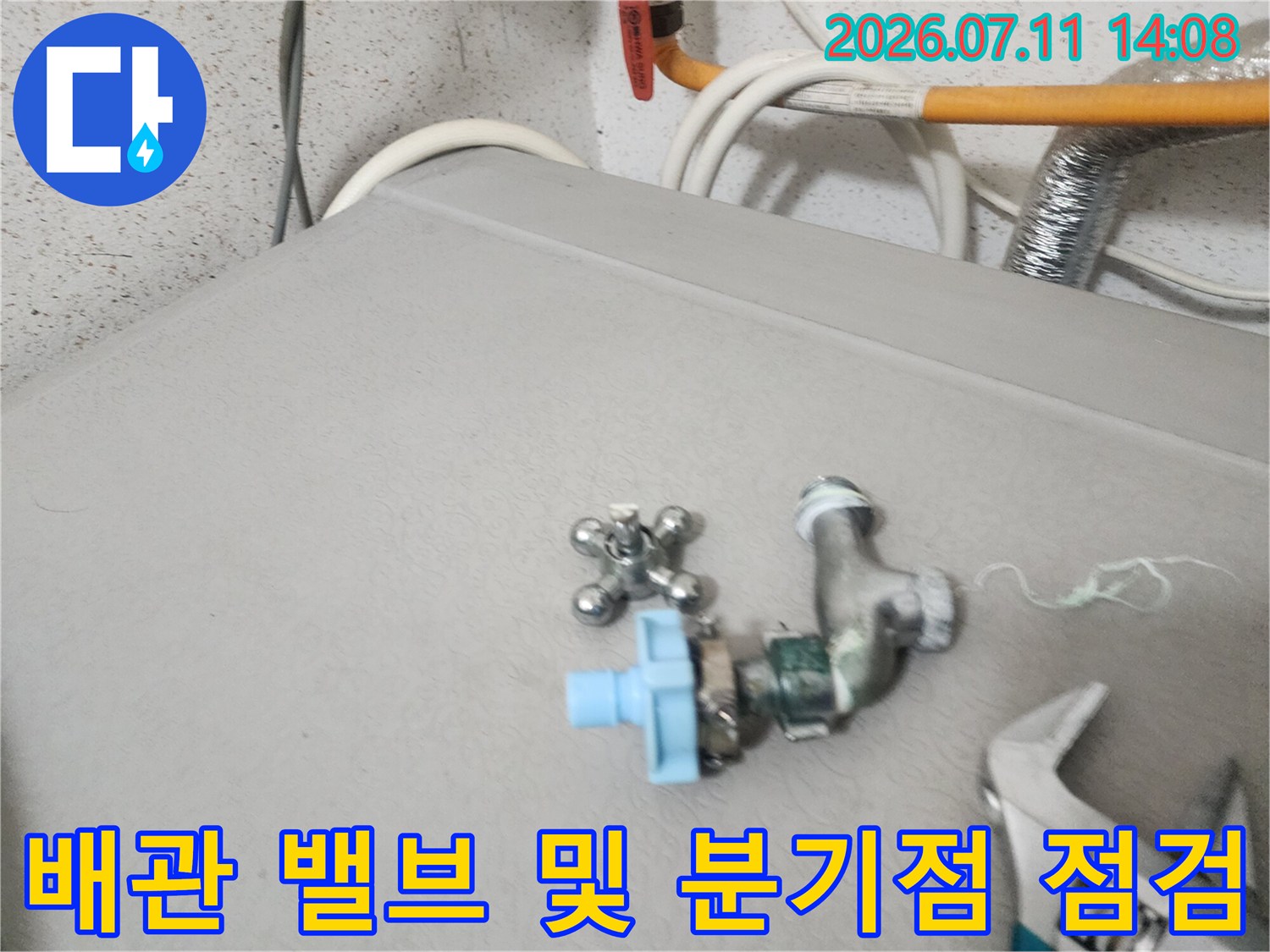 회색 기계 상단에 위치한 파란색 핸들의 배관 밸브와 연결 부위 점검 모습