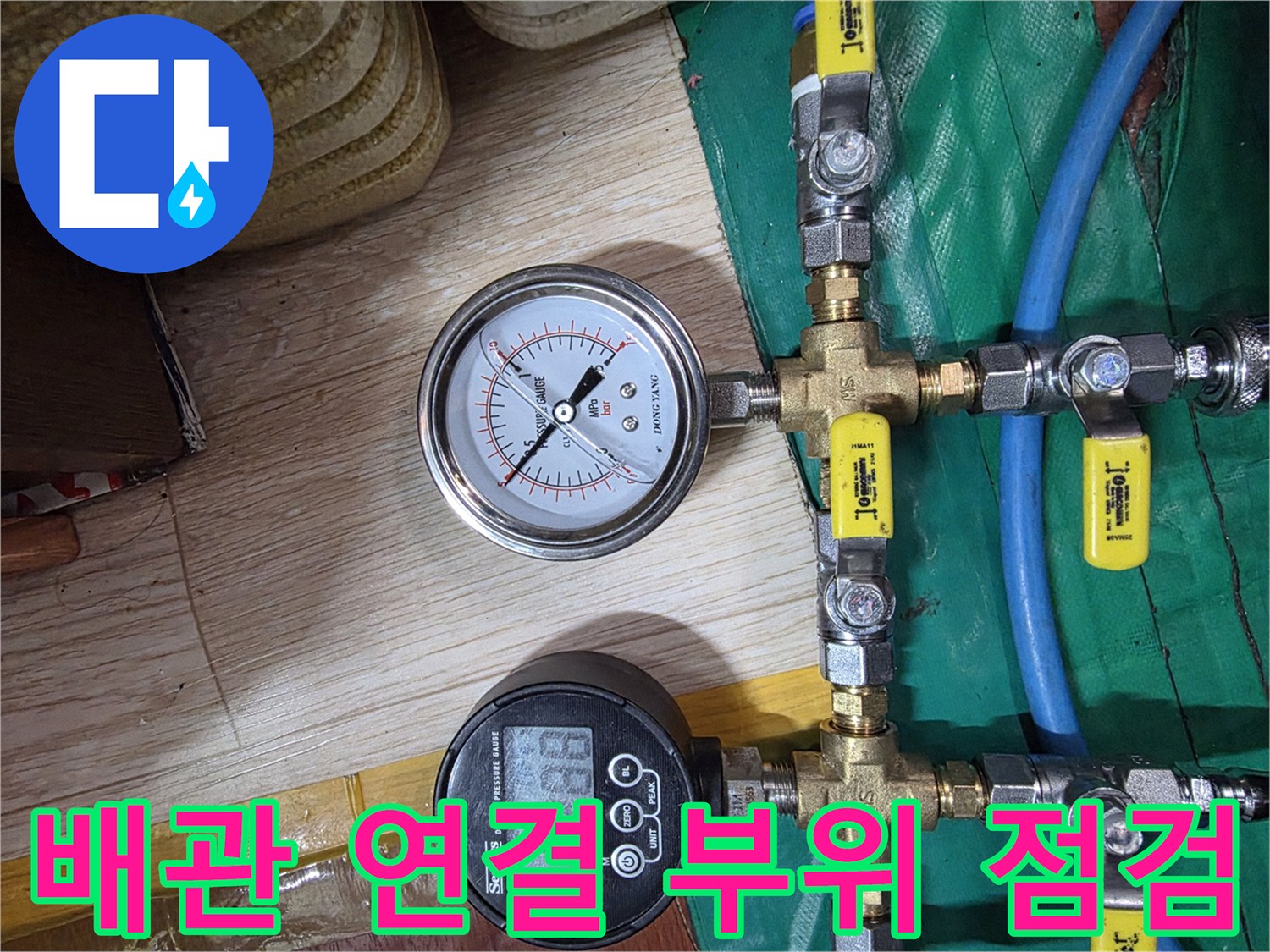 노란색 밸브와 금속 배관이 연결된 압력 측정 장치 모습