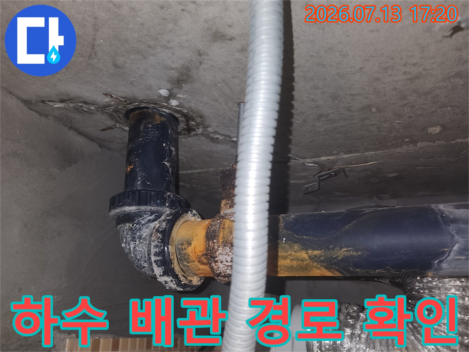 노출된 파란색 하수도 관과 은백색 보호재로 감싼 전선 구간의 점검