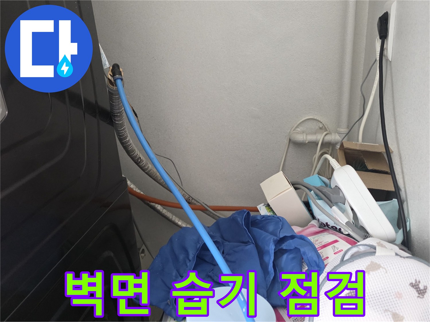 세탁실 배관에 연결된 파란색 호스와 뒤쪽의 은색 자재들