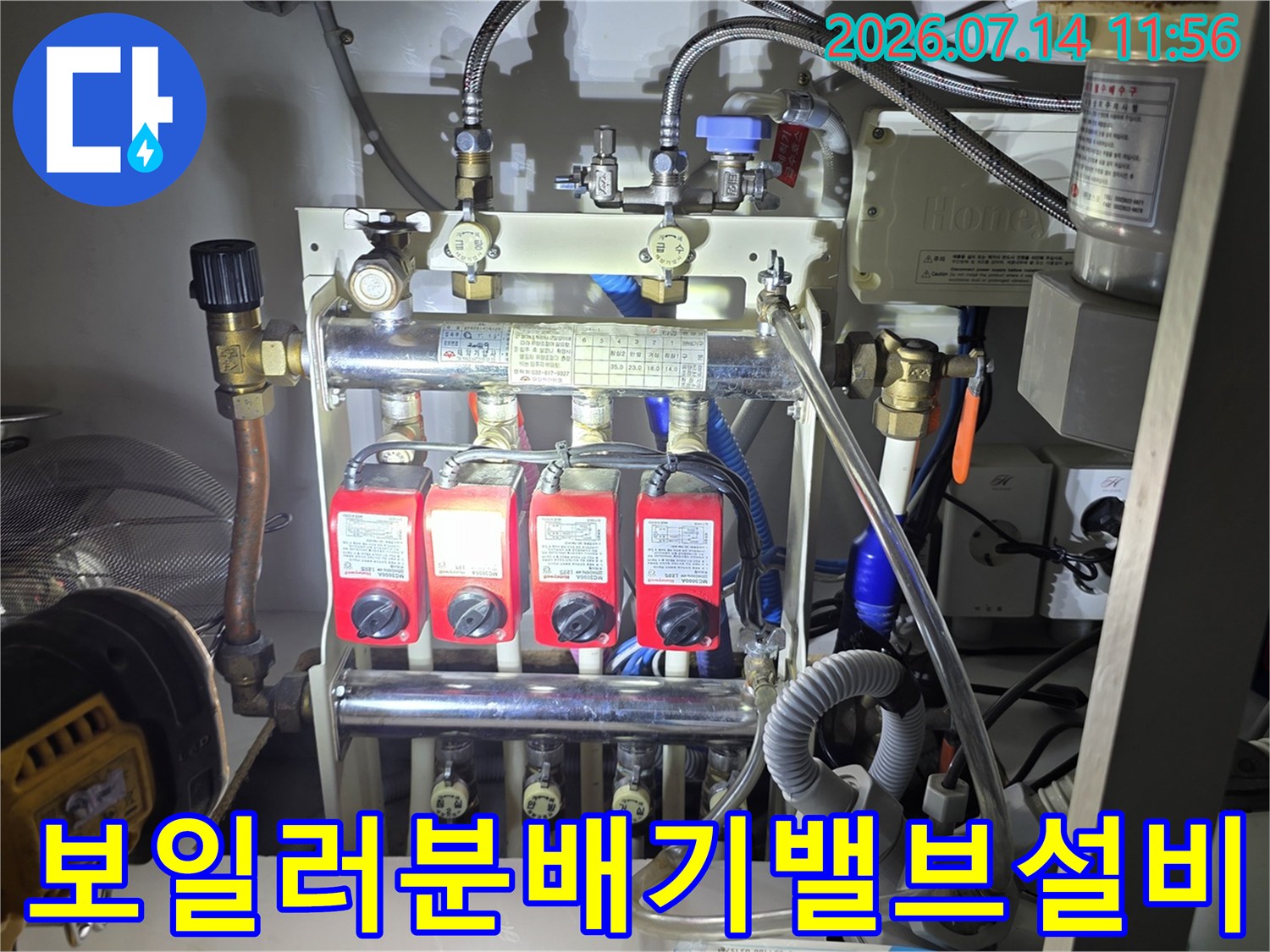 빨간색 밸브가 나란히 설치된 보일러 분배기와 연결된 금속 배관들