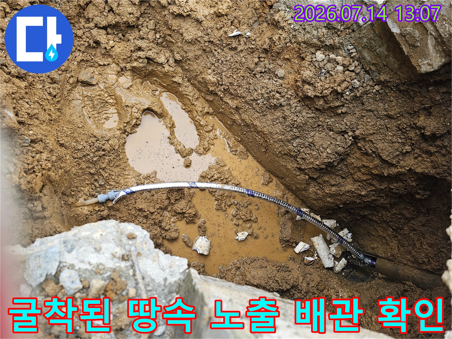 굴착된 지면 아래에 노출된 파란색 수도 배관과 주변의 젖은 토사