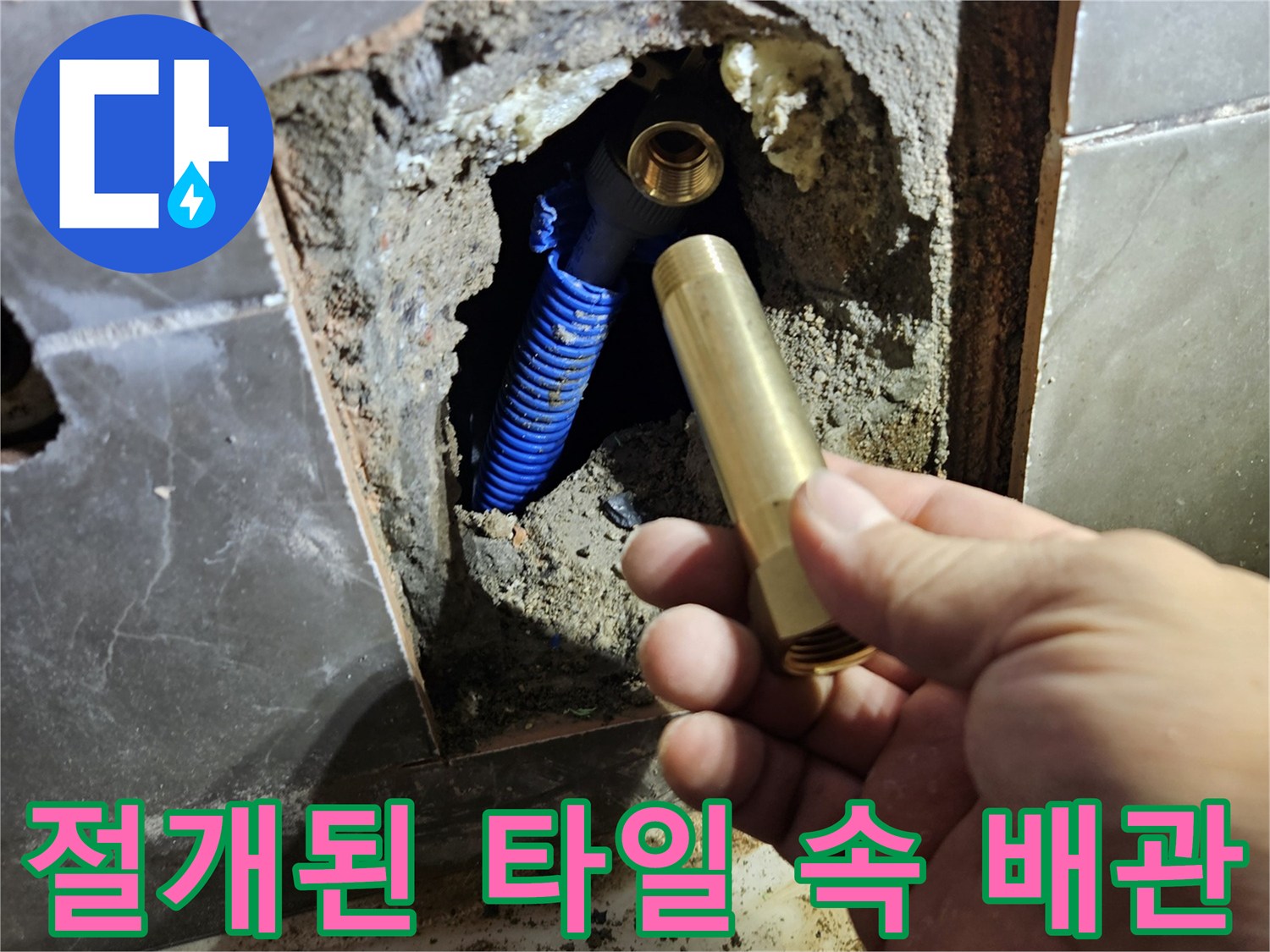 타일 제거 후 노출된 파란색 배관과 황동 소켓 부품