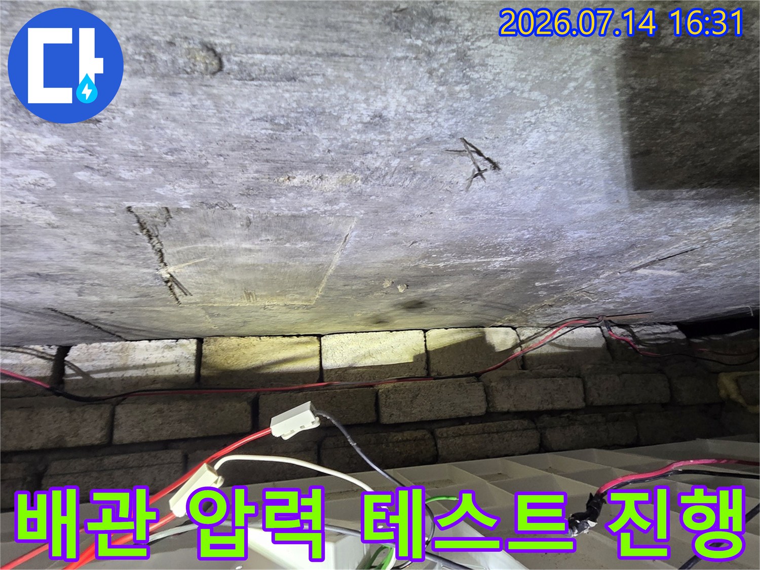 누수 탐지를 위해 배관에 연결된 디지털 계측 장비와 천장 구조물