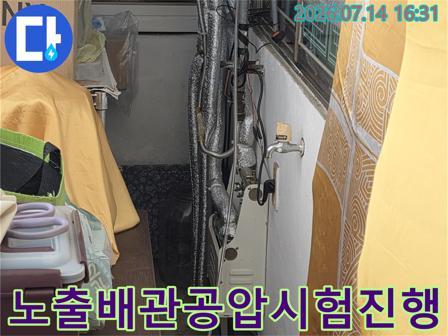 천장 내부에 노출된 수도 배관에 공압 시험기를 연결하여 점검하는 장면