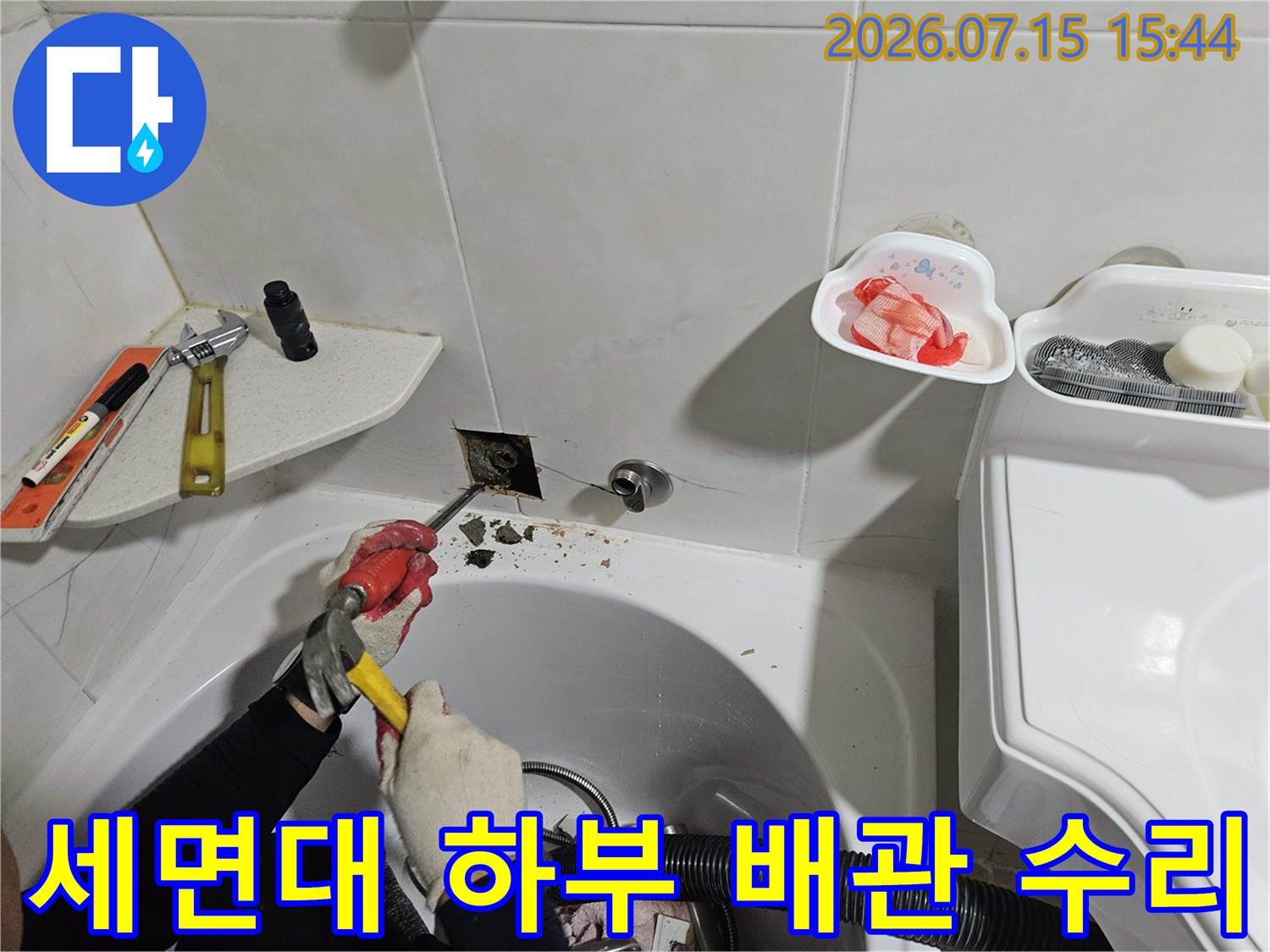 기술자가 세면대 아래 노출된 배관을 점검하며 공구로 작업하는 모습