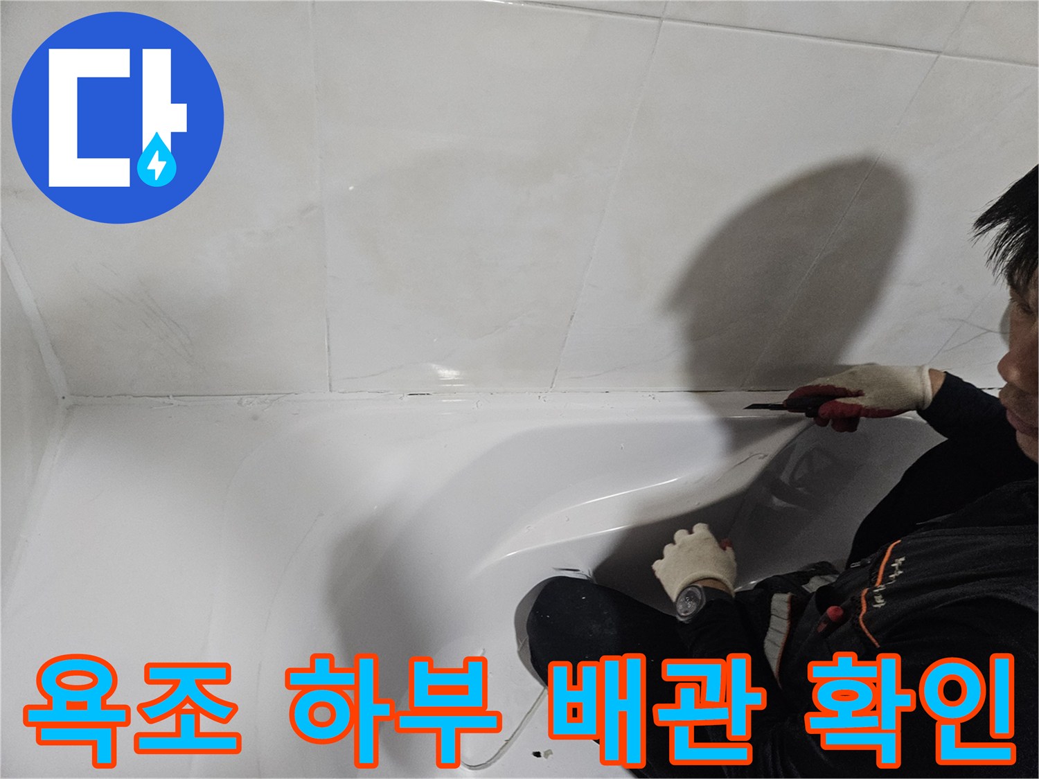 작업자가 욕실 벽면 타일과-욕조 사이를 점검하는 장면입니다