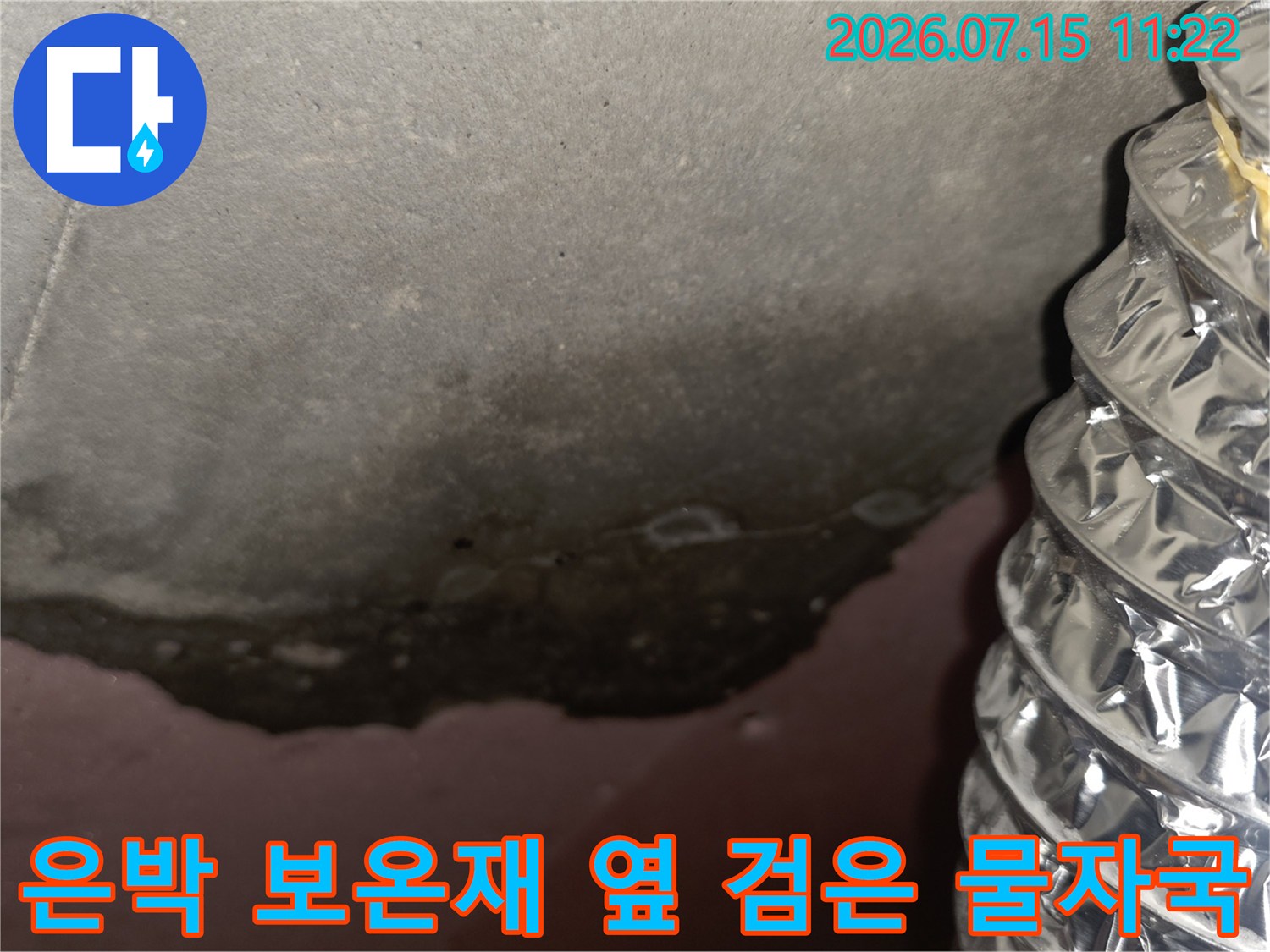 천장 슬라브 표면에 생긴 짙은 색의 누수 얼룩과 인접한 은박 보온 배관 모습