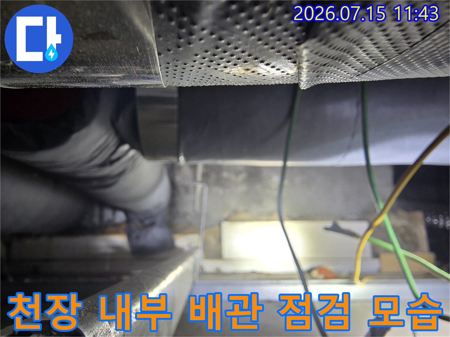 좁은 천장 공간에서-배관과 전선을 점검하고 있는 엔지니어의 모습