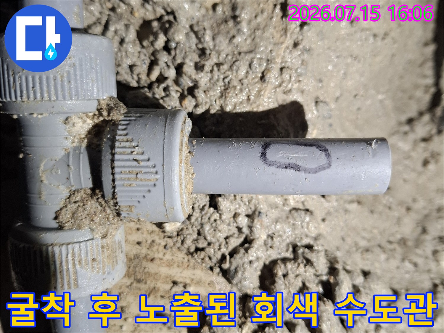 흙 속에 묻혀 있던 회색 플라스틱 배관의 연결 너트와 분기 지점