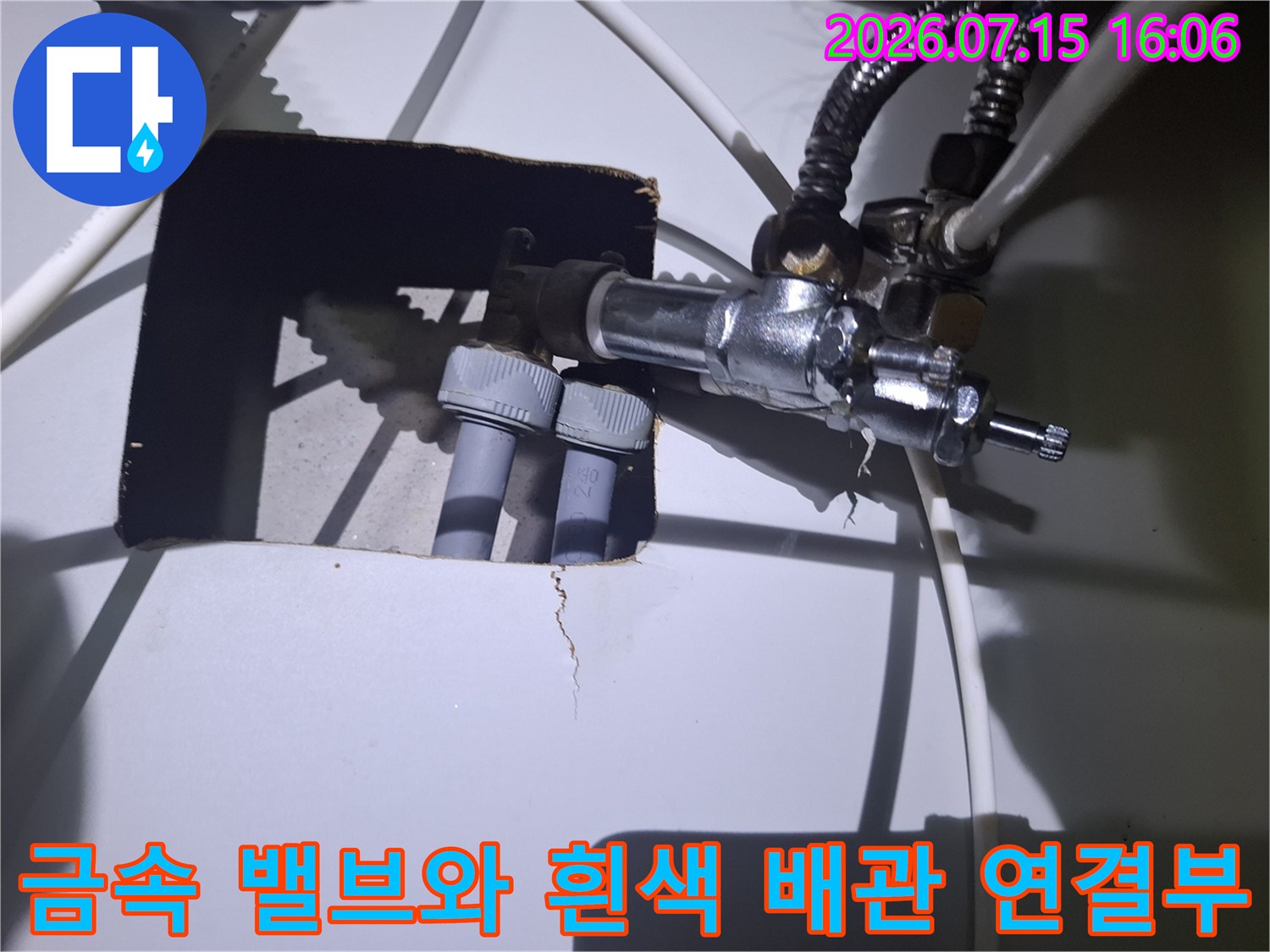 흰색 플라스틱 파이프가 금속제 컨트롤 밸브에 연결되어 있는 상세 사진