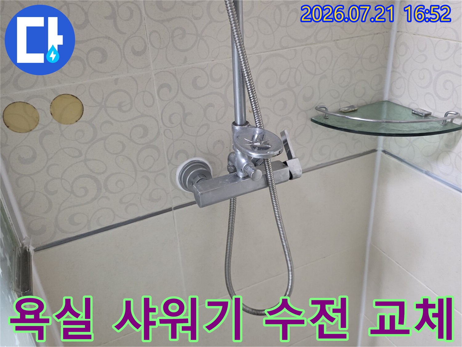 화장실 벽면에 설치된 은색 샤워용품과 배관 연결부