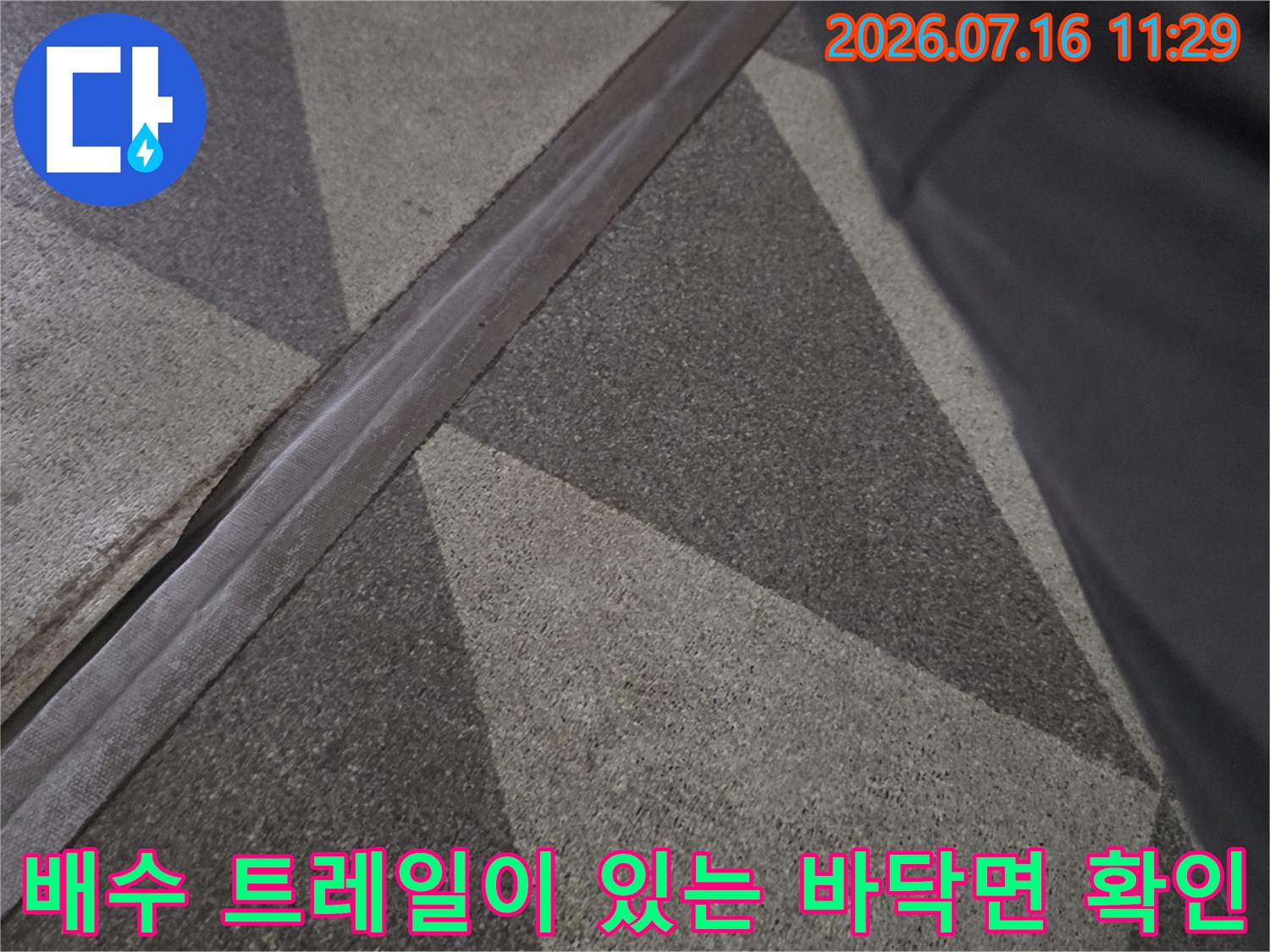 금속 배수재와 타일 사이의 틈새를 조사하는 누수 점검 현장