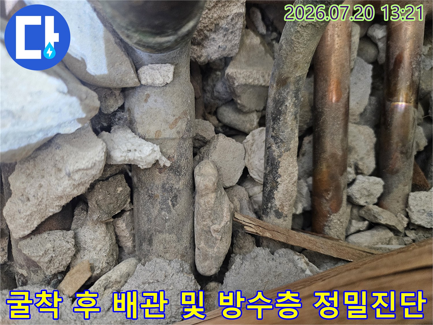 파손된 지점의 노출된 배관과 주변 파편이 섞인 누수 현장 사진