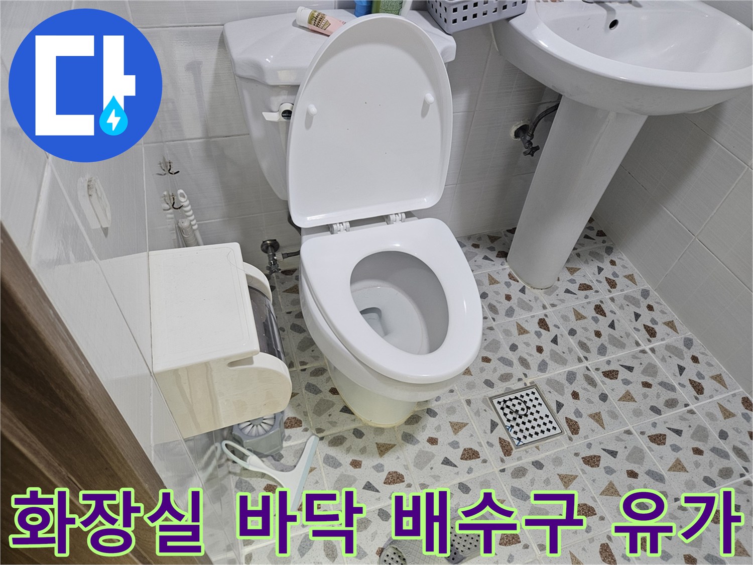 변기 근처의 배수구와 화장실 내부 마감재를 촬영한 사진입니다.