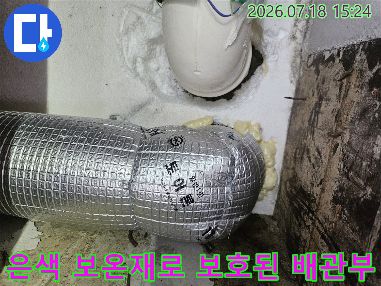 수직으로 배치된 은색 보온재 배관과 주변 구조물 촬영