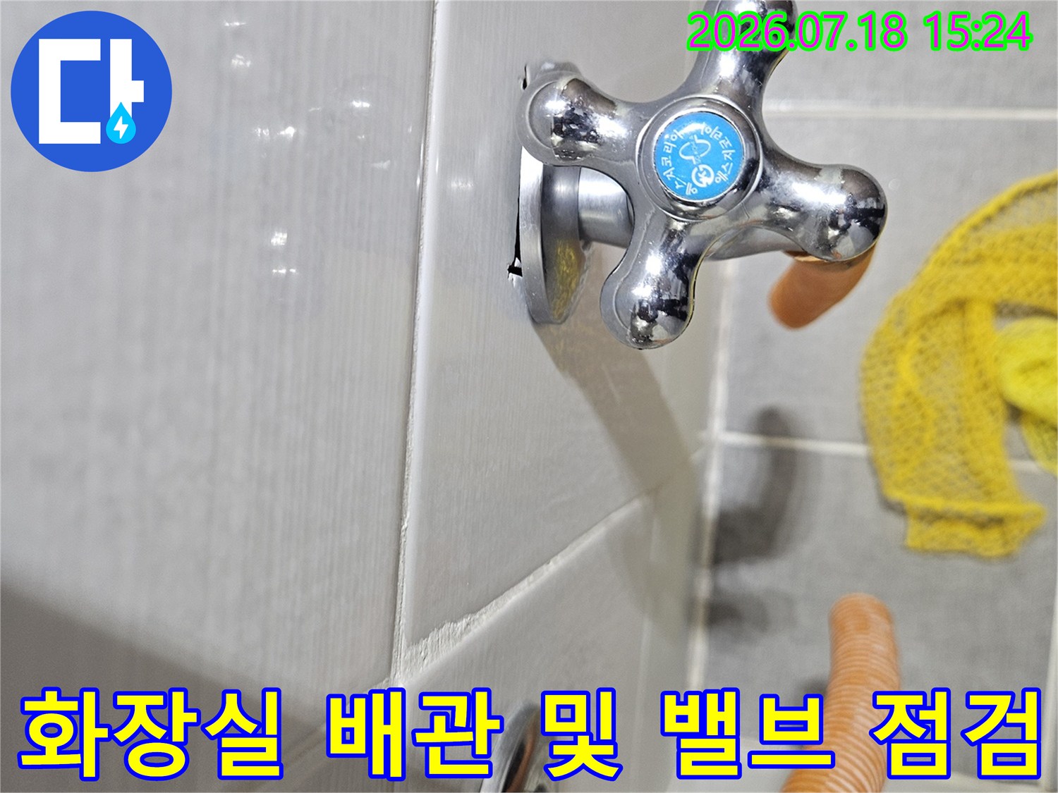 흰색 타일 바닥에 설치된 크롬 소재의 십자형 수전 밸브와 주변부