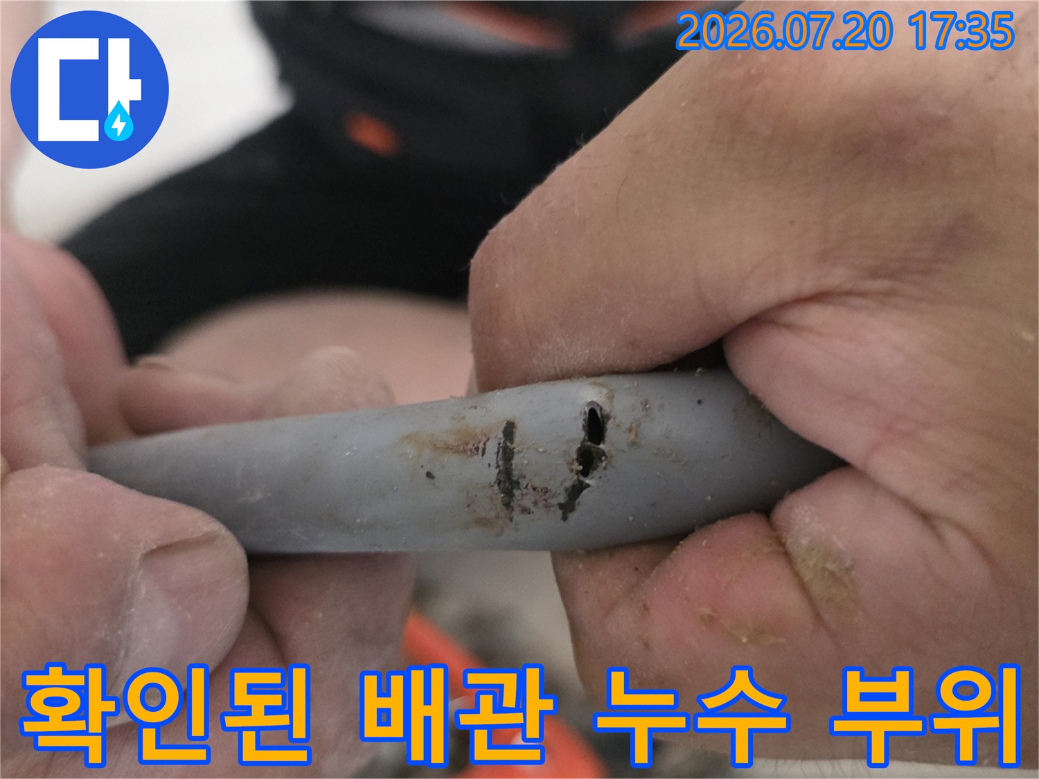 손상된 회색 배관의 파손 구간을 클로즈업하여 보여주는 모습