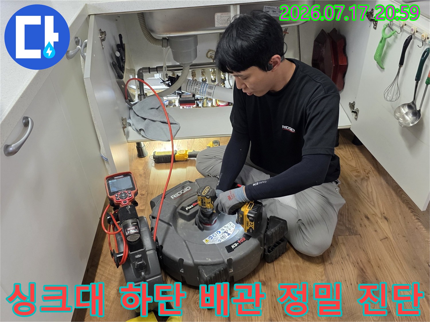 기술자가 싱크대 아래에서 전용 탐지기를 사용하여 배출 경로를 점검하는 사진