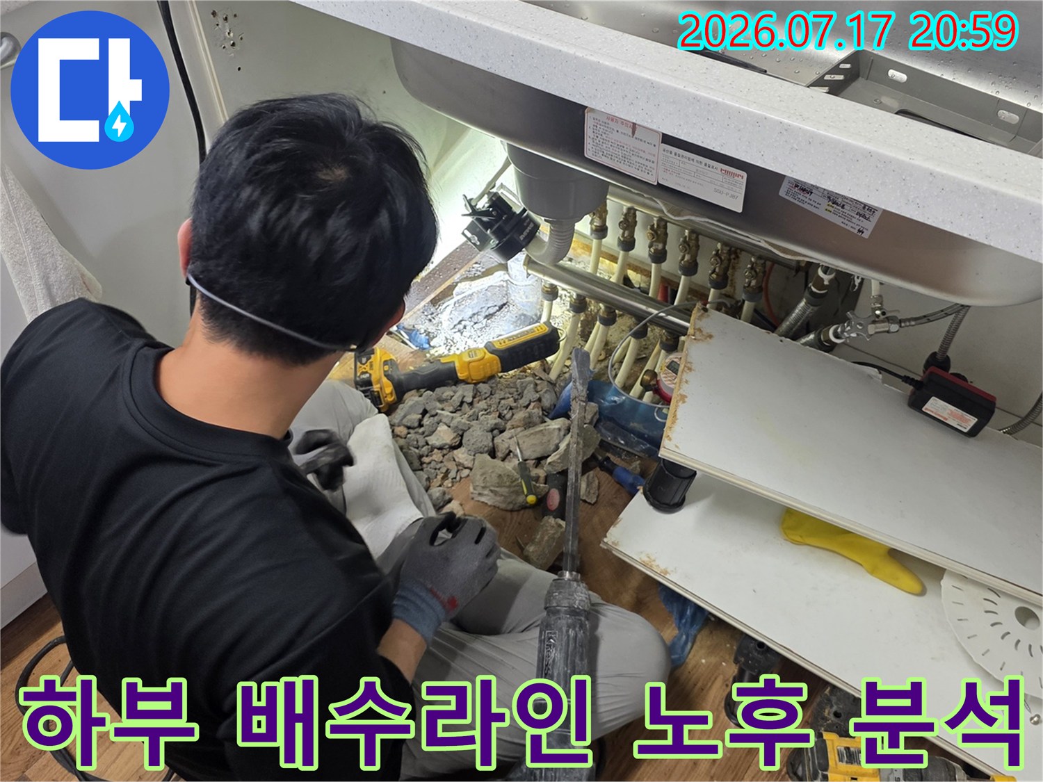 싱크대 아래에 위치한 배수 시스템의 물리적 상태를 면밀히 조사하는 모습