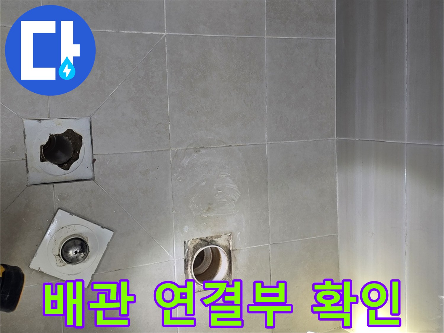 탈거된 배수구 주변의 노출된 배관과 바닥 타일 상태