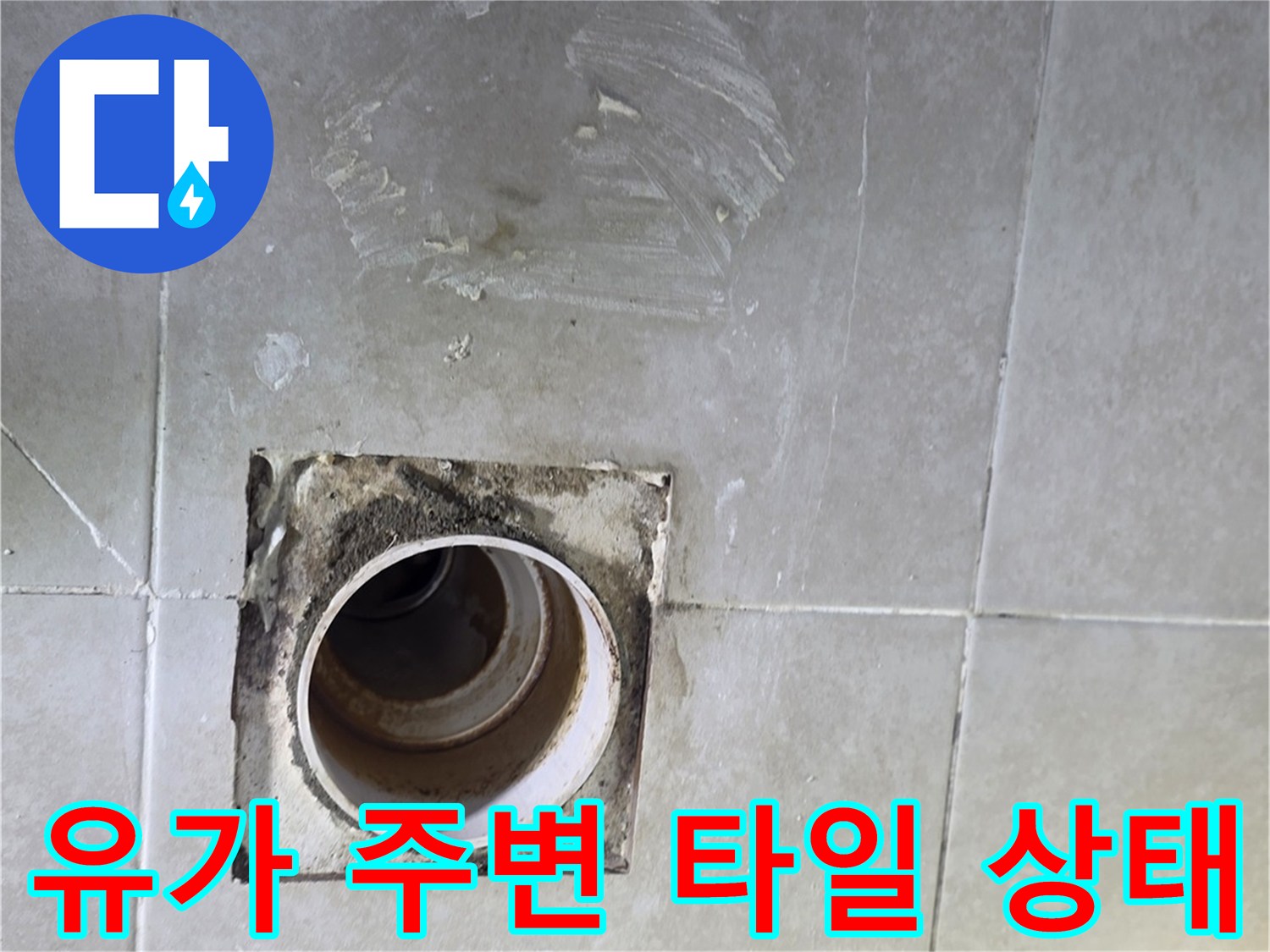 화장실 배수구 주변의 노후된 타일과 배관 입구를 촬영하였습니다.
