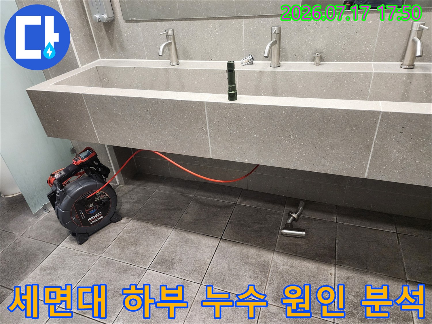 회색 타일 세면대 아래의 배수 파이프와 측정 장비-빨간색 전선 연결 상태